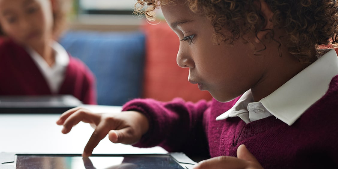 Child in classroom using tablet.