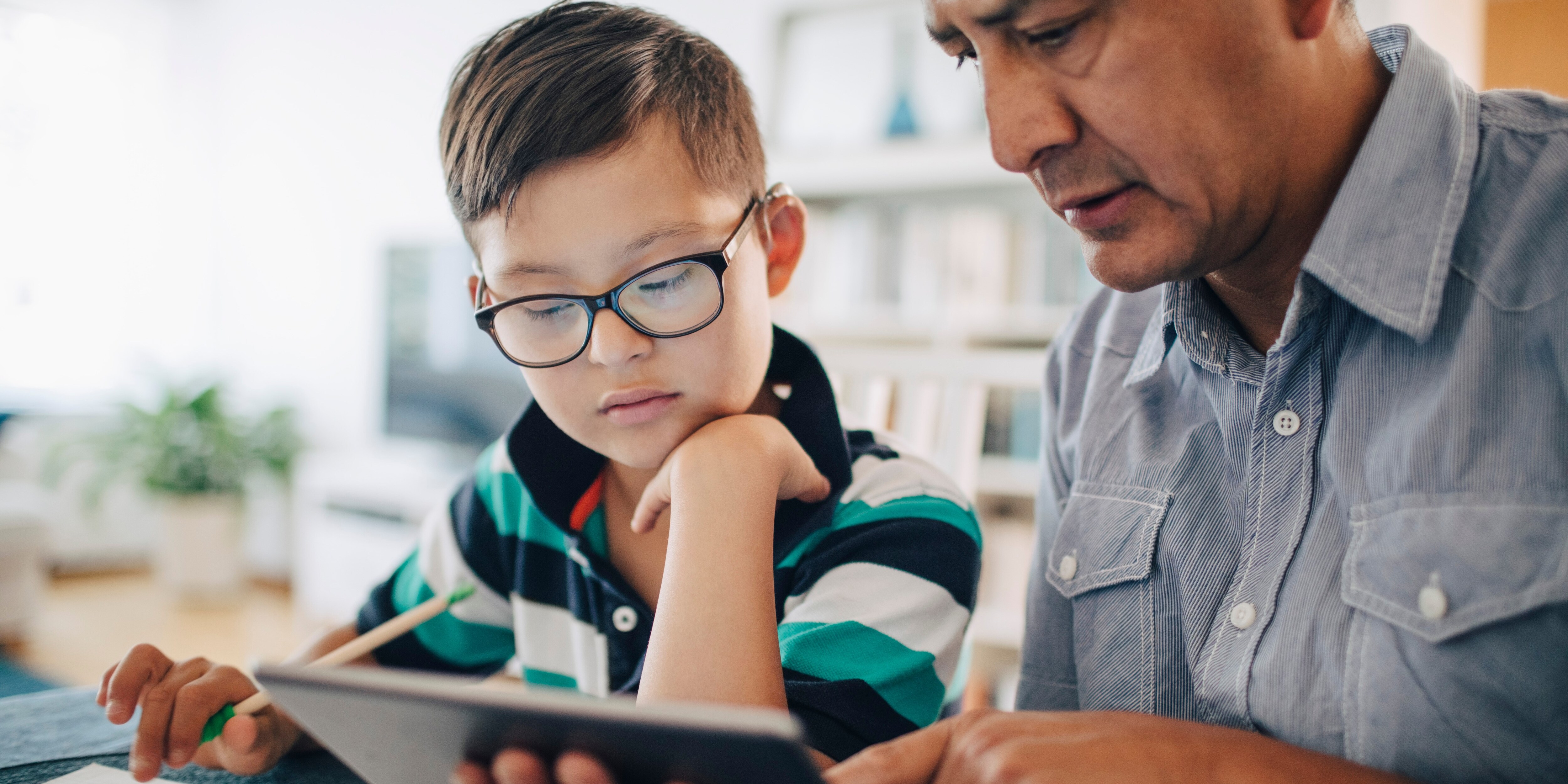 Father and young child working on a tablet together.