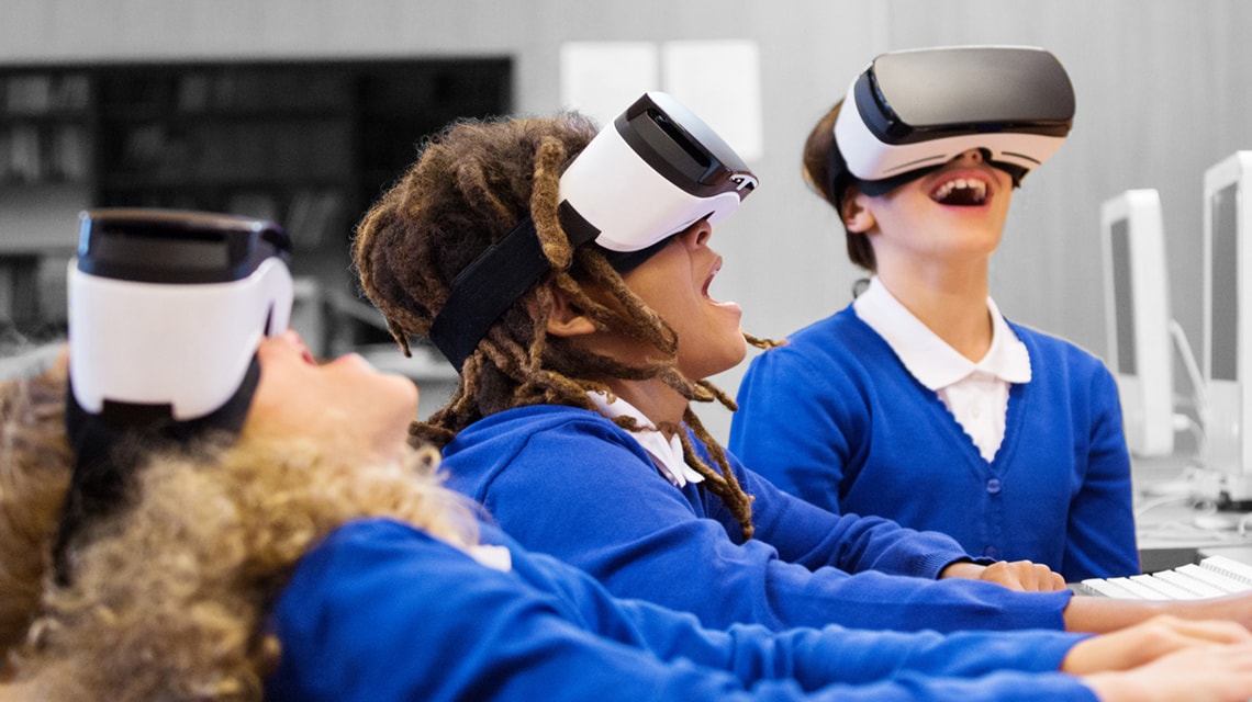 Three primary school students wearing VR headsets in a classroom