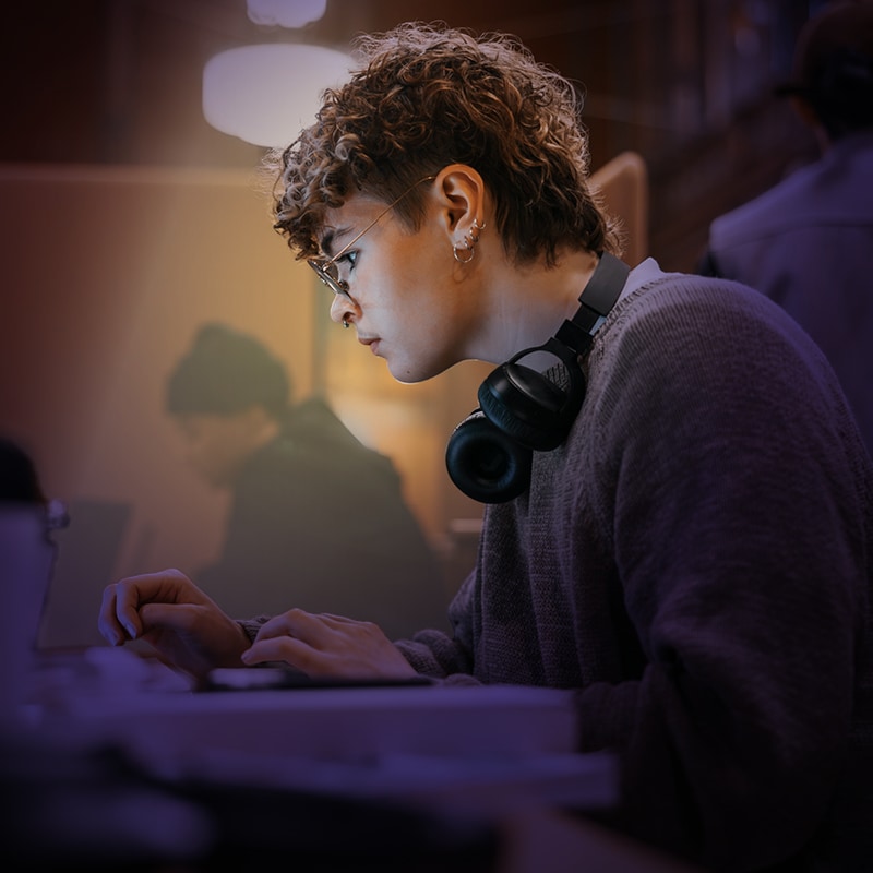 Young man in a suit holding paper looking at a computer screen