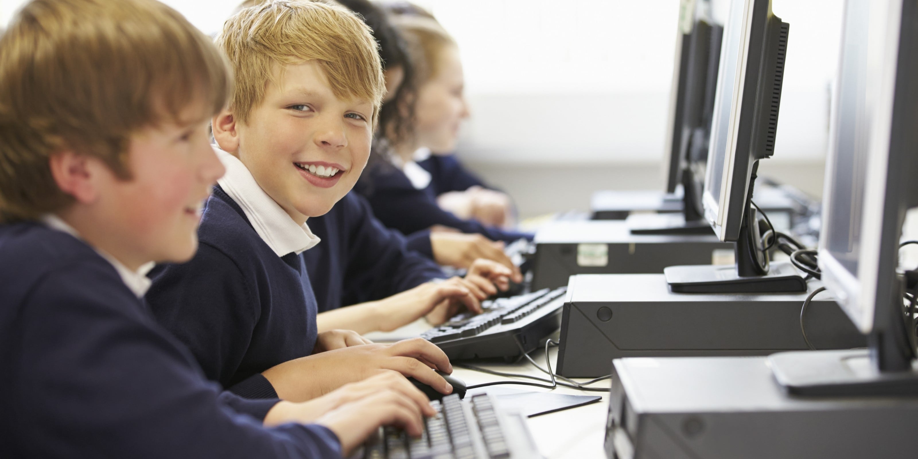 Female teacher helping pupil using computer in classroom