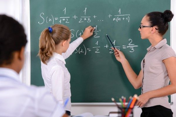 Teacher and learner writing on a blackboard