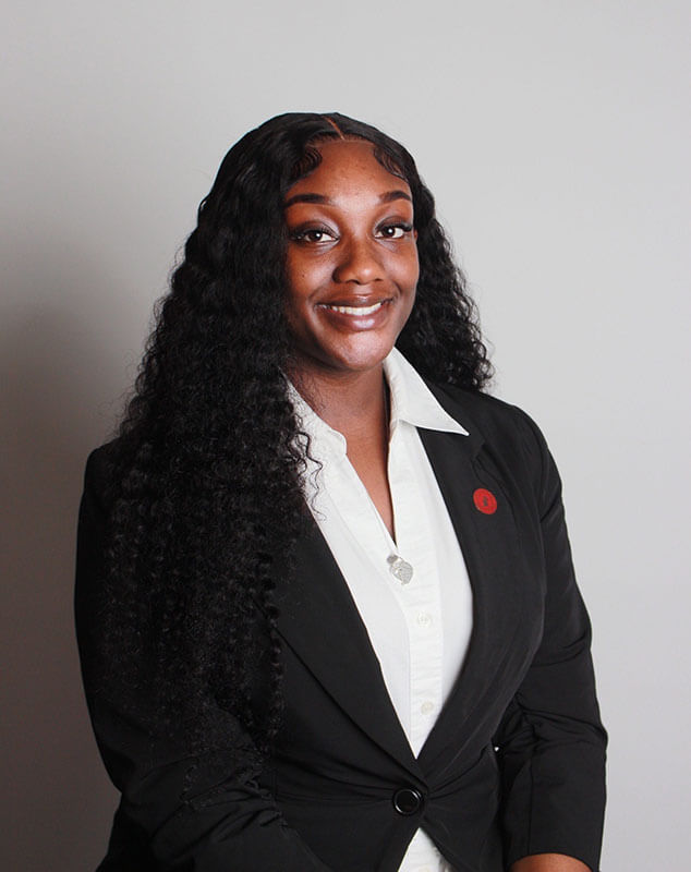 Blog author Aissa has long black wavy hair and is wearing a dark blazer over a white blouse.