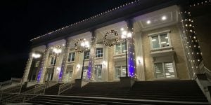 A nighttime photo of a campus building with tall pillars and holiday decorations.