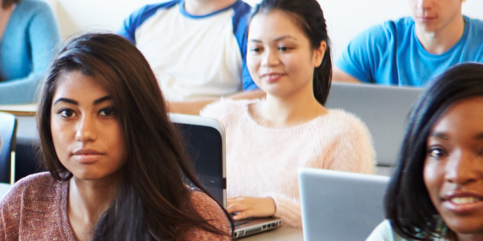 A diverse group of students sitting in a classroom, focused and engaged.