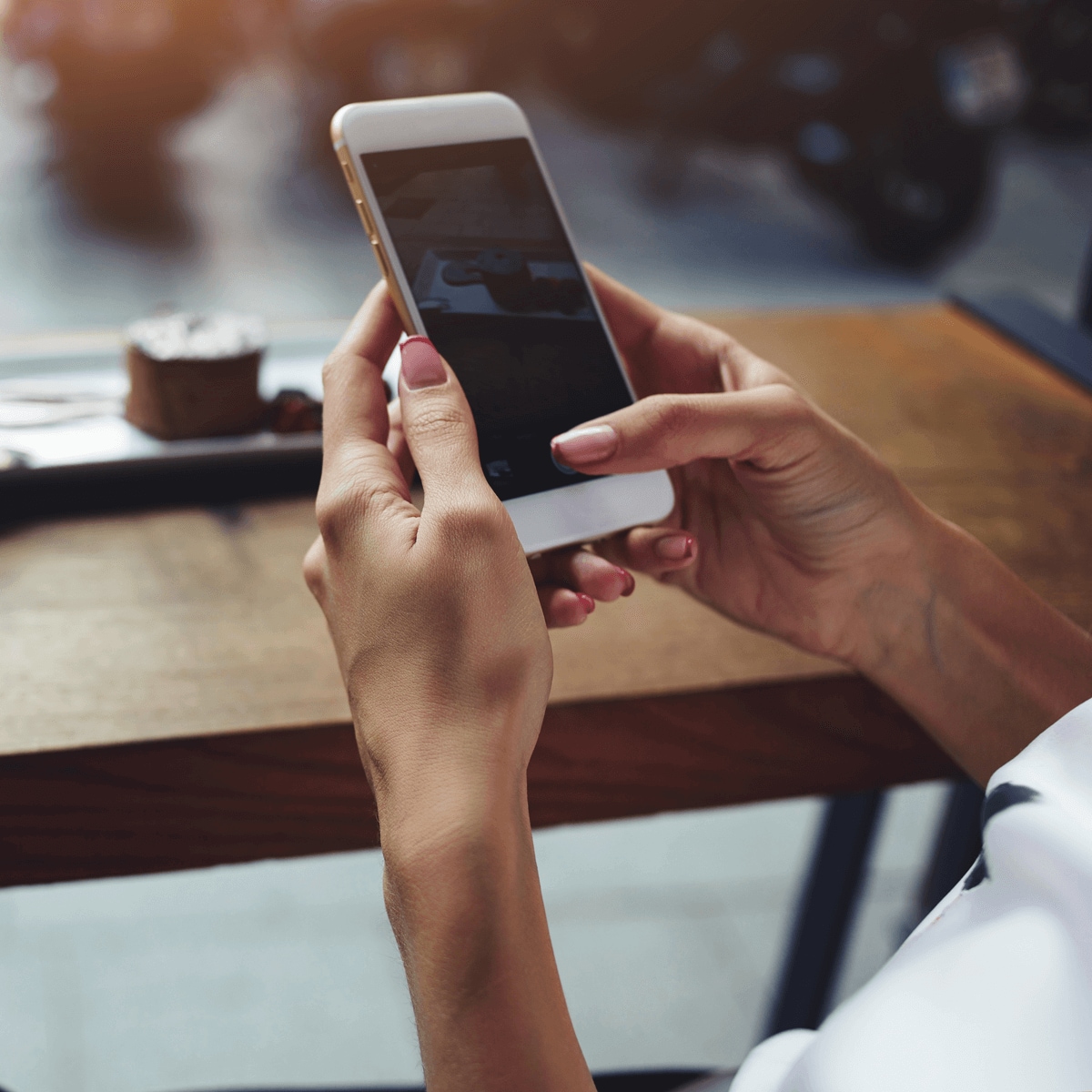 A person texting on a phone while sitting at a coffee table.