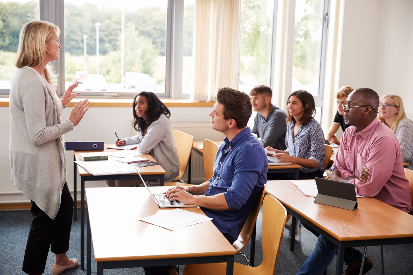 Instructor standing in front of a class of diverse adult students 