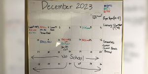 A large dry-erase calendar with various student commitments listed, including classes and meetings.