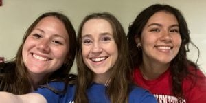 Three young college women smiling for a selfie.