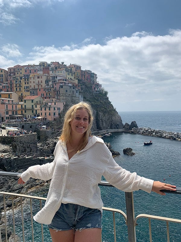 Blog author Emma is leaning against a railing in an overlook area of Cinque Terre, Italy.