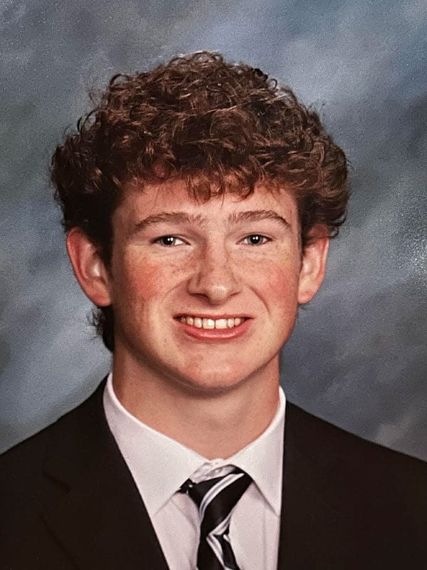 Blog author Jack has light brown short curly hair and is wearing a dark blazer over a white shirt and black and white striped necktie.