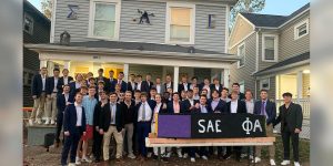 A group of fraternity men standing in a group outside their fraternity house.