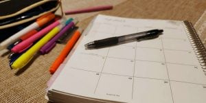 A calendar notebook and several pens.