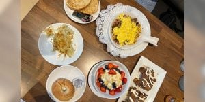 A tabletop featuring a variety of dishes featuring eggs, potatoes, and bagels.