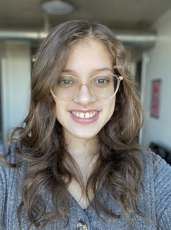 Blog author Liana has light brown wavy hair and is wearing glasses and a blue cardigan.