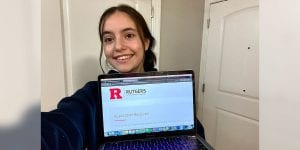 A young woman holding a computer screen with a message from Rutgers stating ‘Application Received’.