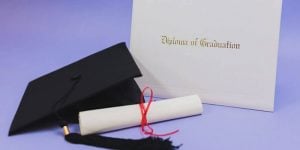 A computer generated graphic featuring a graduation cap, a rolled diploma, and a whit diploma cover labeled Certificate of Graduation.
