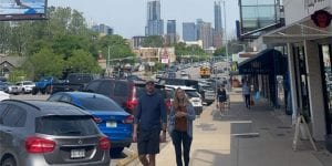 A man and a woman walking on a city sidewalk in Austin, Texas.