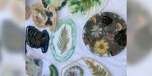 A collection of about 9 acrylic art pieces featuring items found in nature such as leaves and flowers.