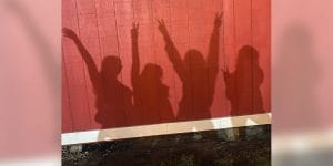 The shadows of 4 people cast on a red wooden wall.