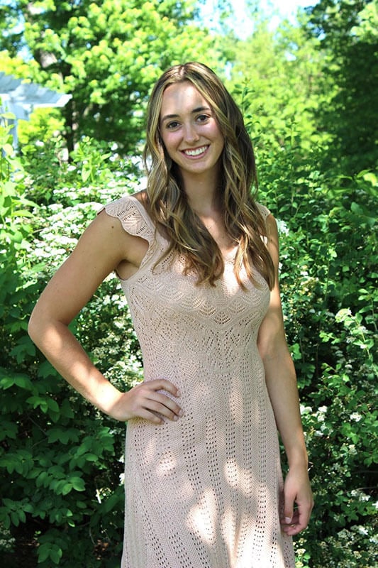 Blog author Tatum is standing outside in front of a large flowering tree. She has dark blonde wavy hair and is wearing a sleeveless ecru dress.