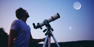 Guy with a telescope looking up at the moon.