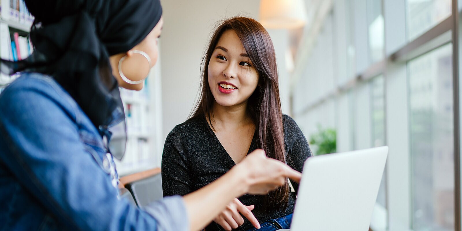 Two students discussing content on the laptop in front of them