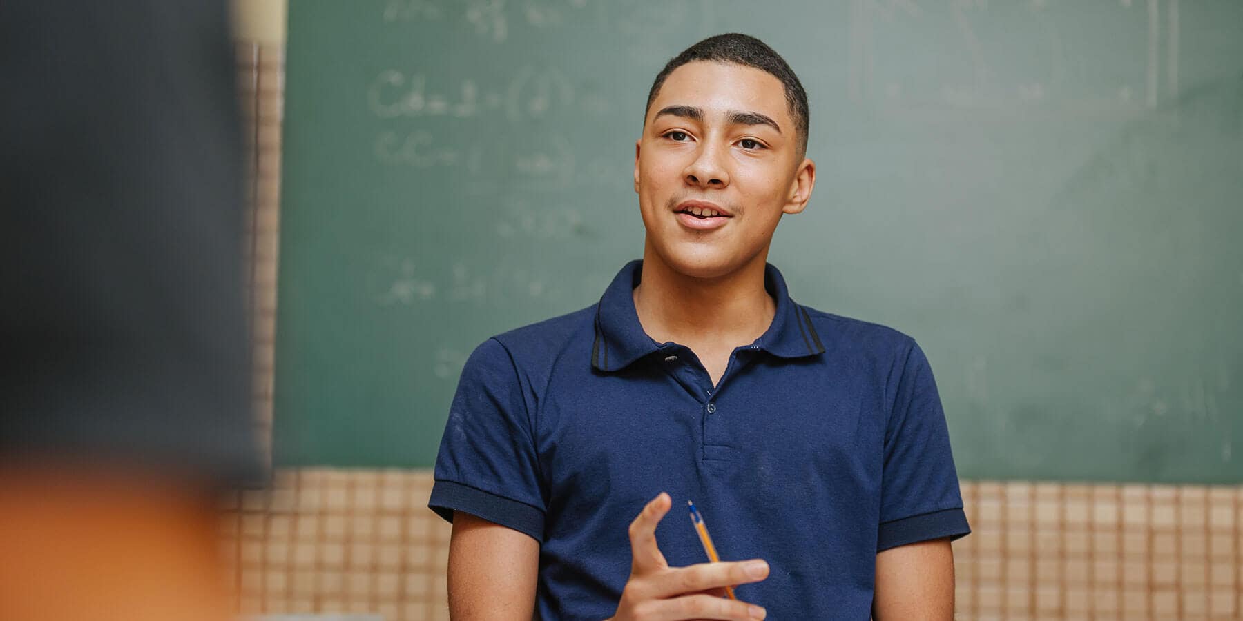 Student standing in from of a green board