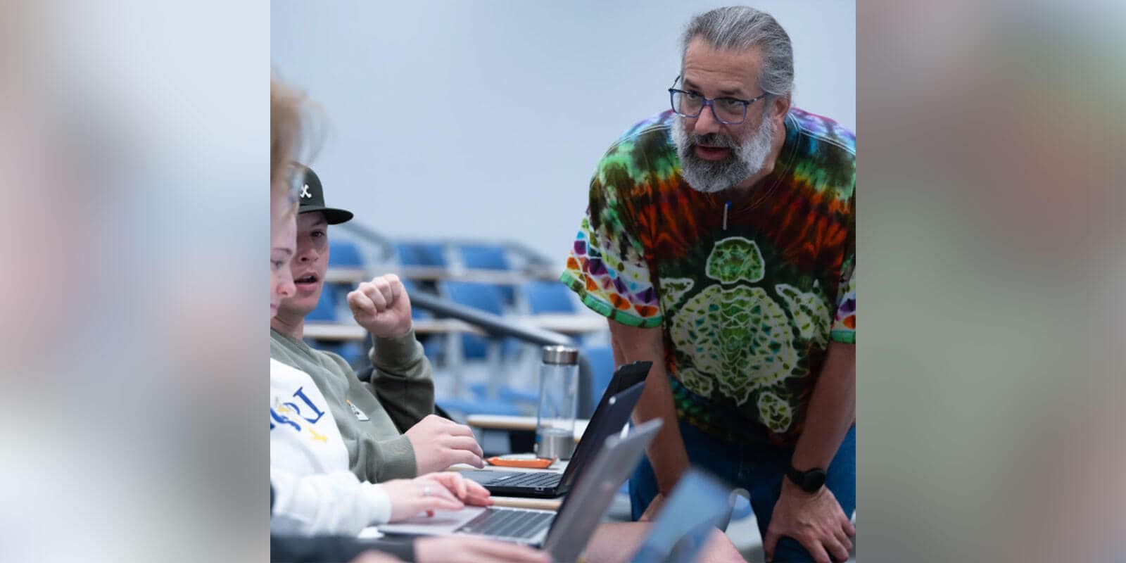 Eric Simon teaching two students seated with laptops.