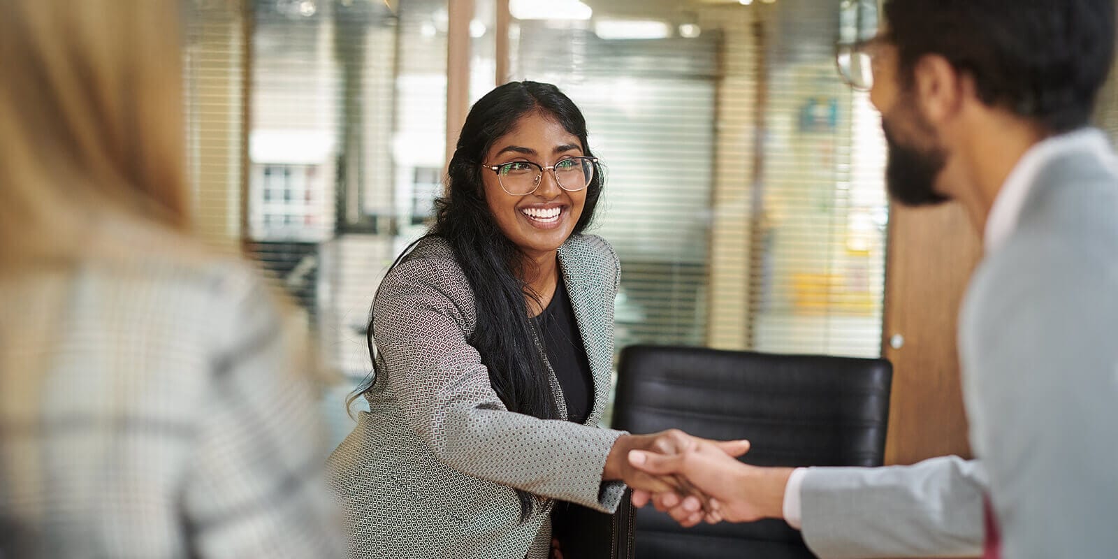 A man and a woman shaking hands in a professional setting