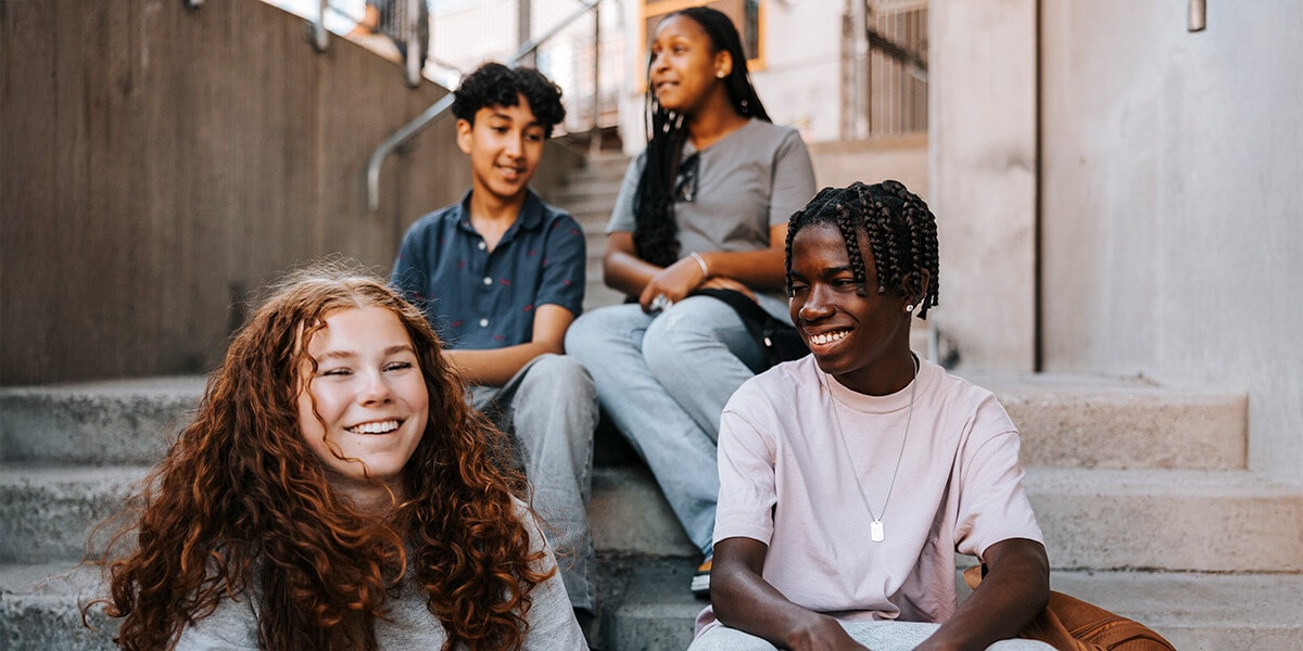 A group of four students sitting on steps, talking with each other