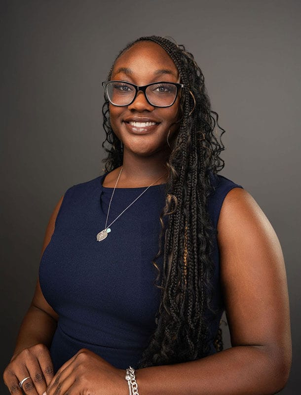 Blog author Aissatou has long dark curly hair and is wearing a royal blue sleeveless shirt.