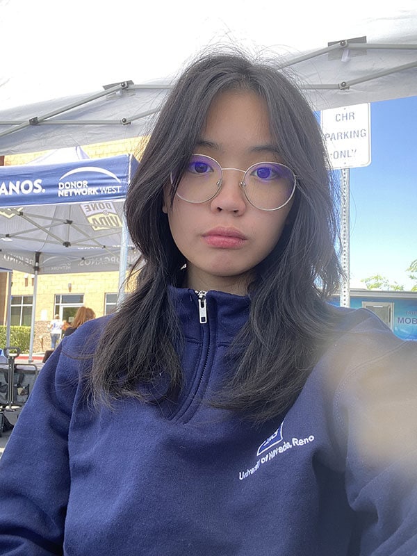 The blog author, Alexis is wearing gold wire-rimmed glasses and a University of Nevada Reno dark blue zip up and has long black hair.