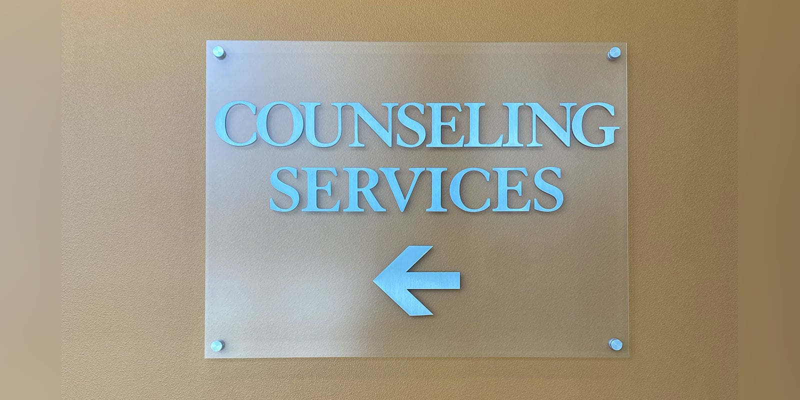 The image shows a sign with the words "Counseling Services" in light blue and an arrow pointing the way posted on a wall.