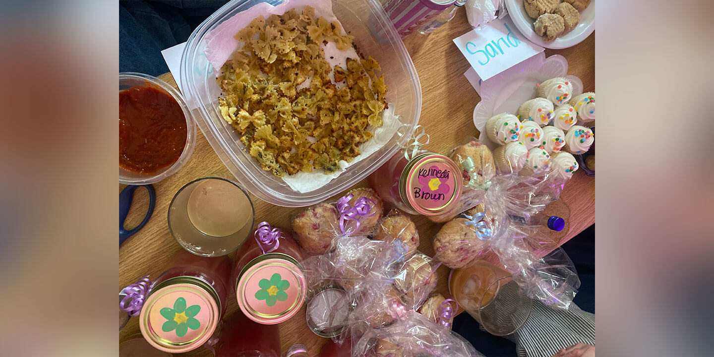 A table full of party food including various snacks and festive cupcakes.
