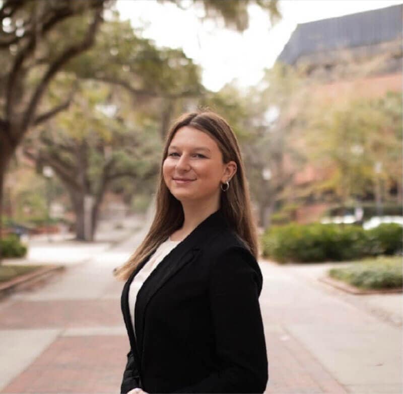 The blog author has long brown hair and is wearing a black blazer with a white shirt.
