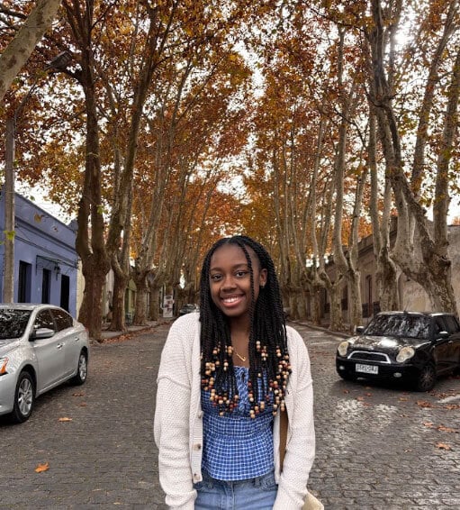 The blog author, Cameron, has long dark braids with beads on the ends and is wearing a blue gingham top with a white sweater and jeans.