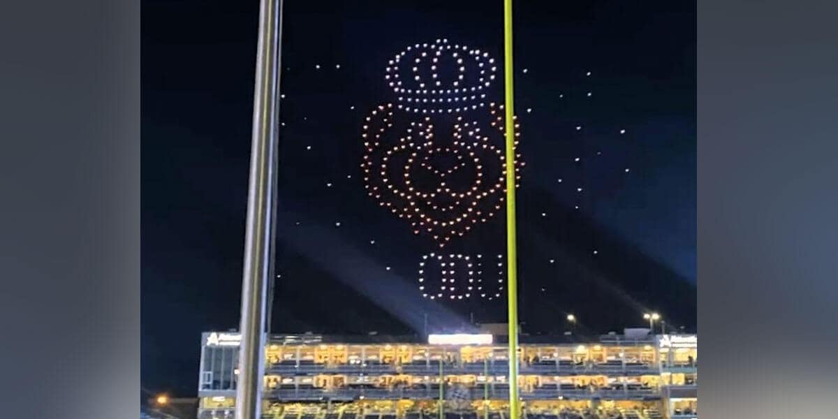 Light display of a crowned lion with the letters ODU underneath at night made up of drones flying over a stadium.