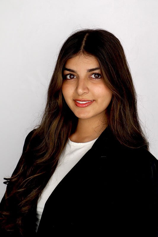 The blog author has long dark hair and is wearing a black blazer with a white shirt.