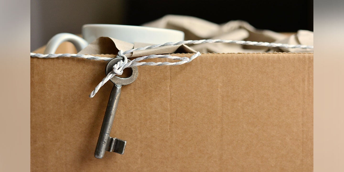 A cardboard packing box with an old-fashioned metal key draped from a string over the side.