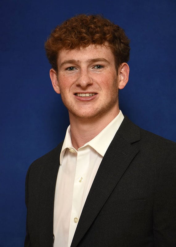 The blog author has curly red hair and is wearing a black blazer with a white button-down shirt.
