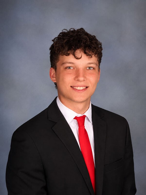 The blog author, Jose, has brown hair, and is wearing a dark sport coat, white shirt, and a red tie.