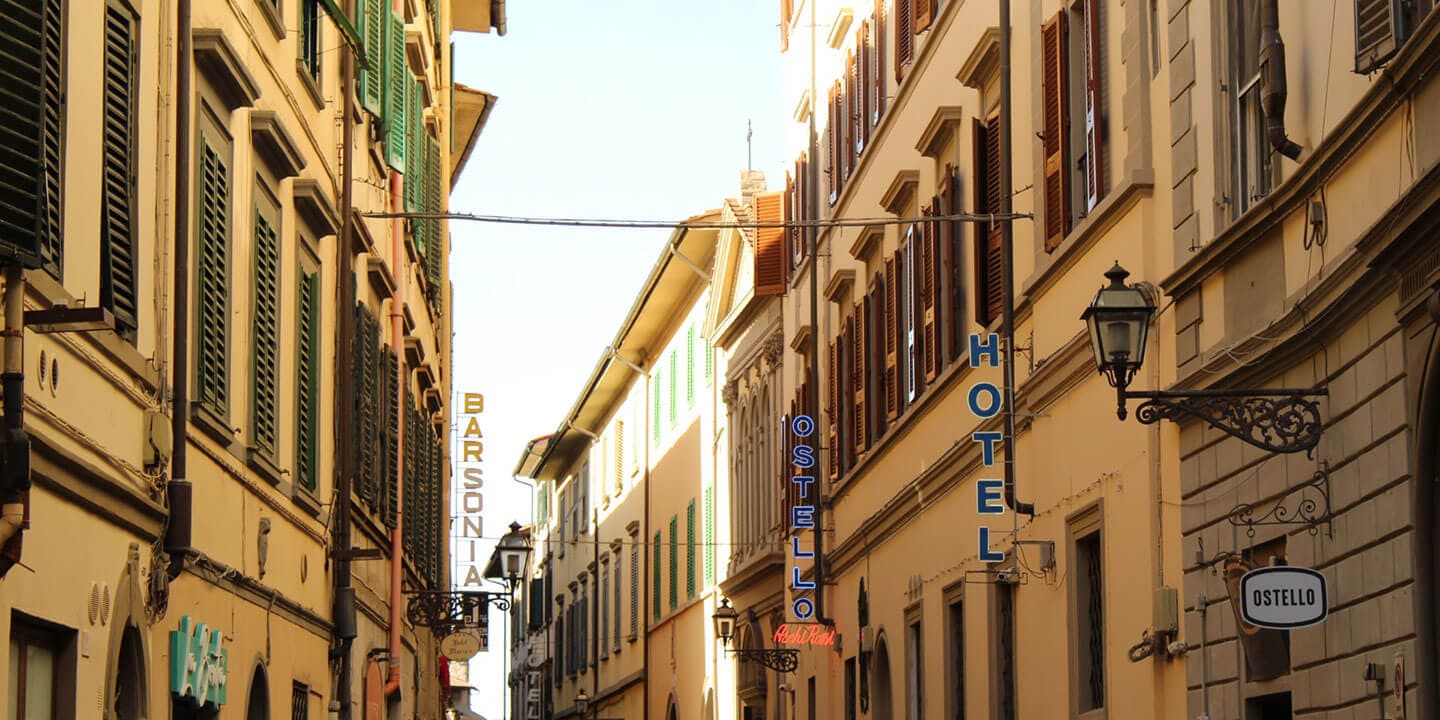Image shows an old European town street filled with hotels and hostels.