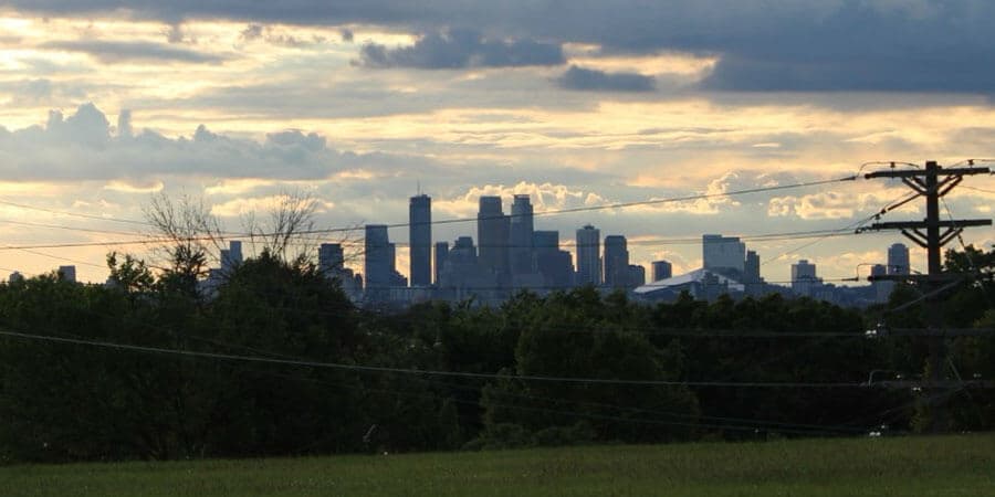 A skyline at sunrise with trees and powerlines in the foreground.