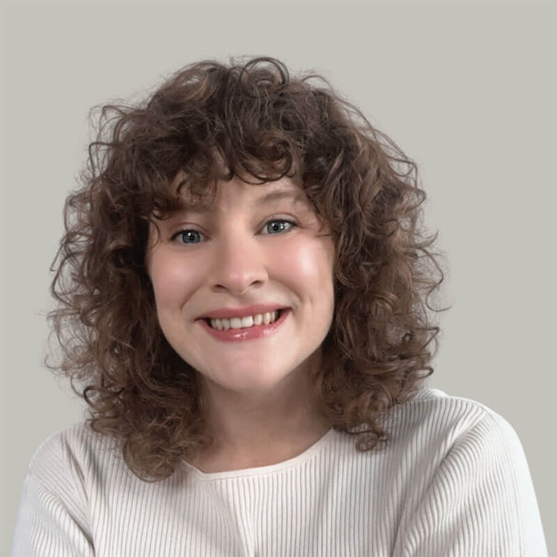 Blog author Katelyn has shoulder-length curly brown hair and is wearing a white crewneck sweater.