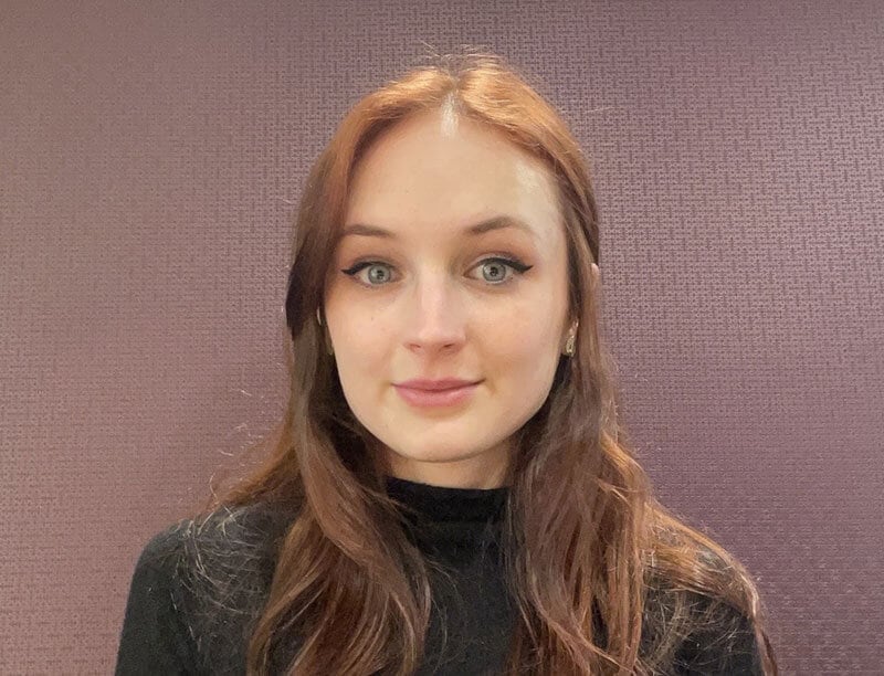The blog author has long red hair and is wearing a black shirt.