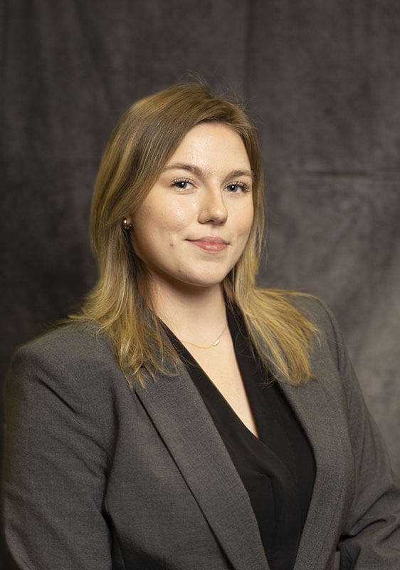 A studio headshot of blog author Lyndsi. She has dark blonde hair and is wearing a dark grey blazer over a black blouse.