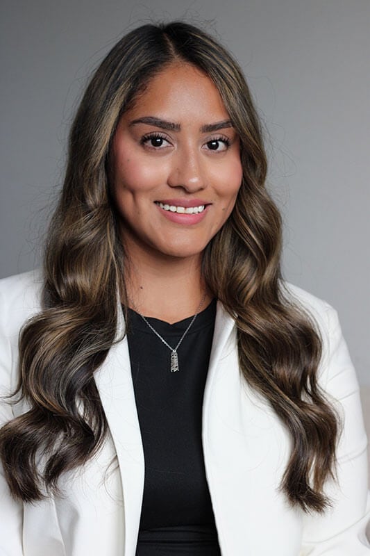 The blog author has long dark hair and is wearing a white blazer over a black shirt with a silver necklace.