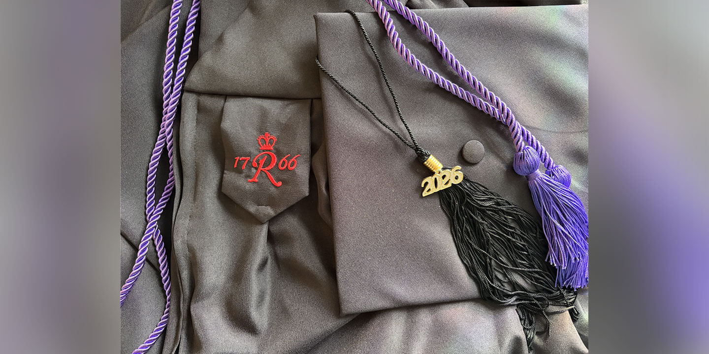 A graduation gown, cap with tassel, and purple graduation cord.
