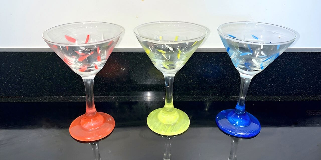 Three hand painted martini glasses in red, yellow, and blue.